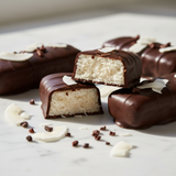 Unreal Dark Chocolate Coconut bars broken open showing white coconut filling on marble
